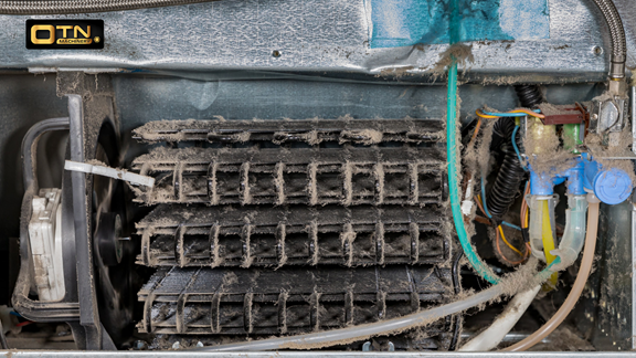 A dusty and worn-out air conditioner unit showcasing a dirty filter, tangled wires, and clean condenser coils, in need of maintenance or repair.