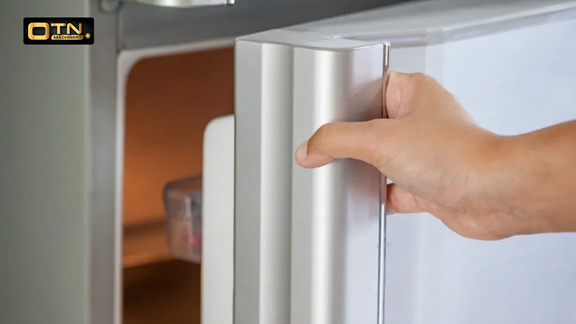  A person's hand opening the door of a white refrigerator, with a partial view inside the fridge. the otn logo is visible in the corner.