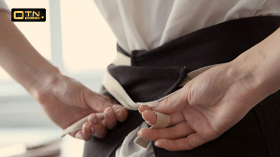 a person tying a band on a black and white apron