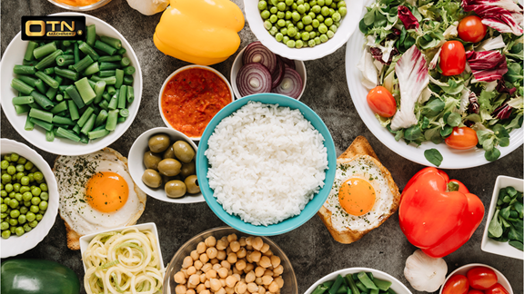 Assorted healthy foods like vegetables, grains, and eggs arranged neatly on a table.