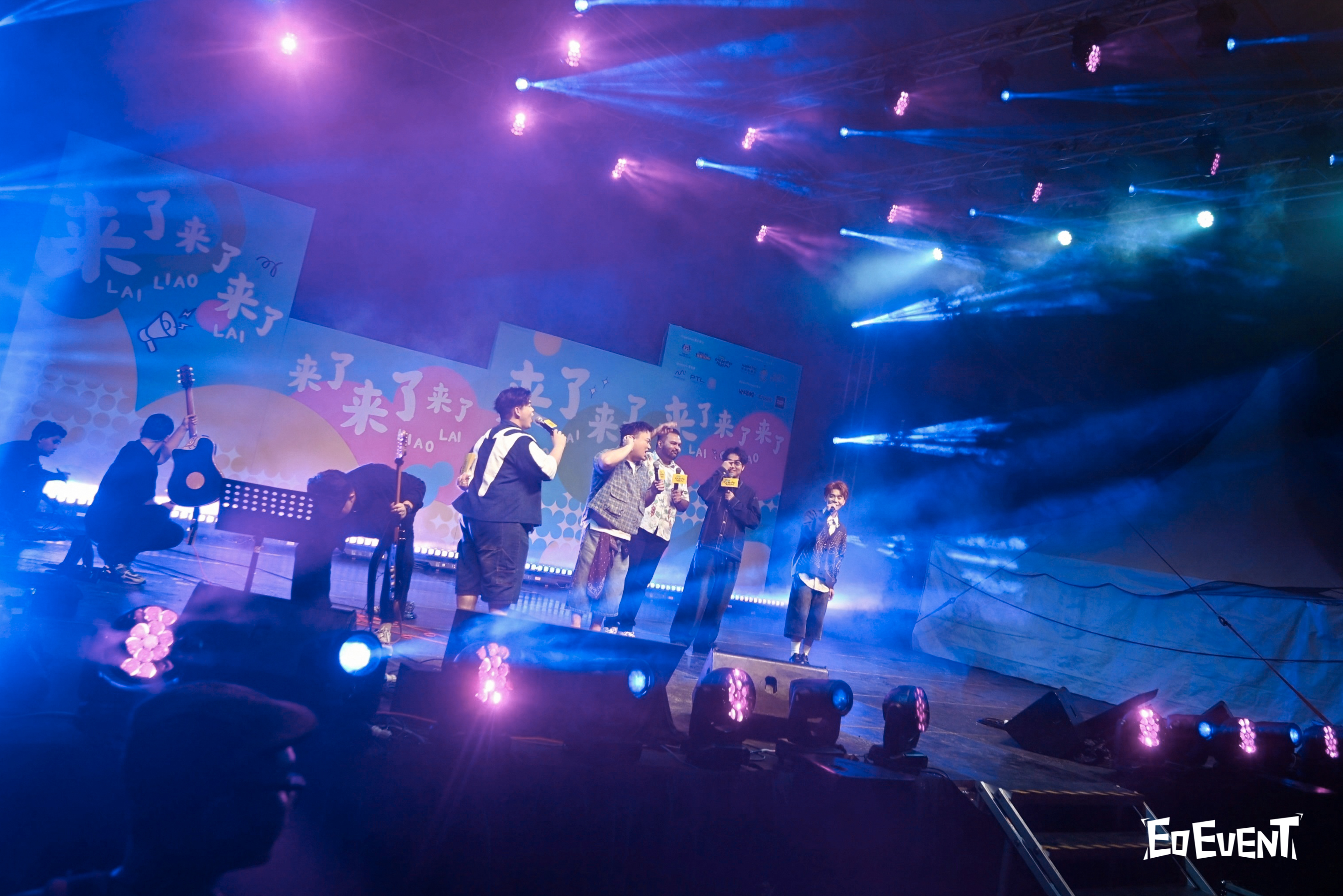 Performer on stage jumping with arms open under spotlights