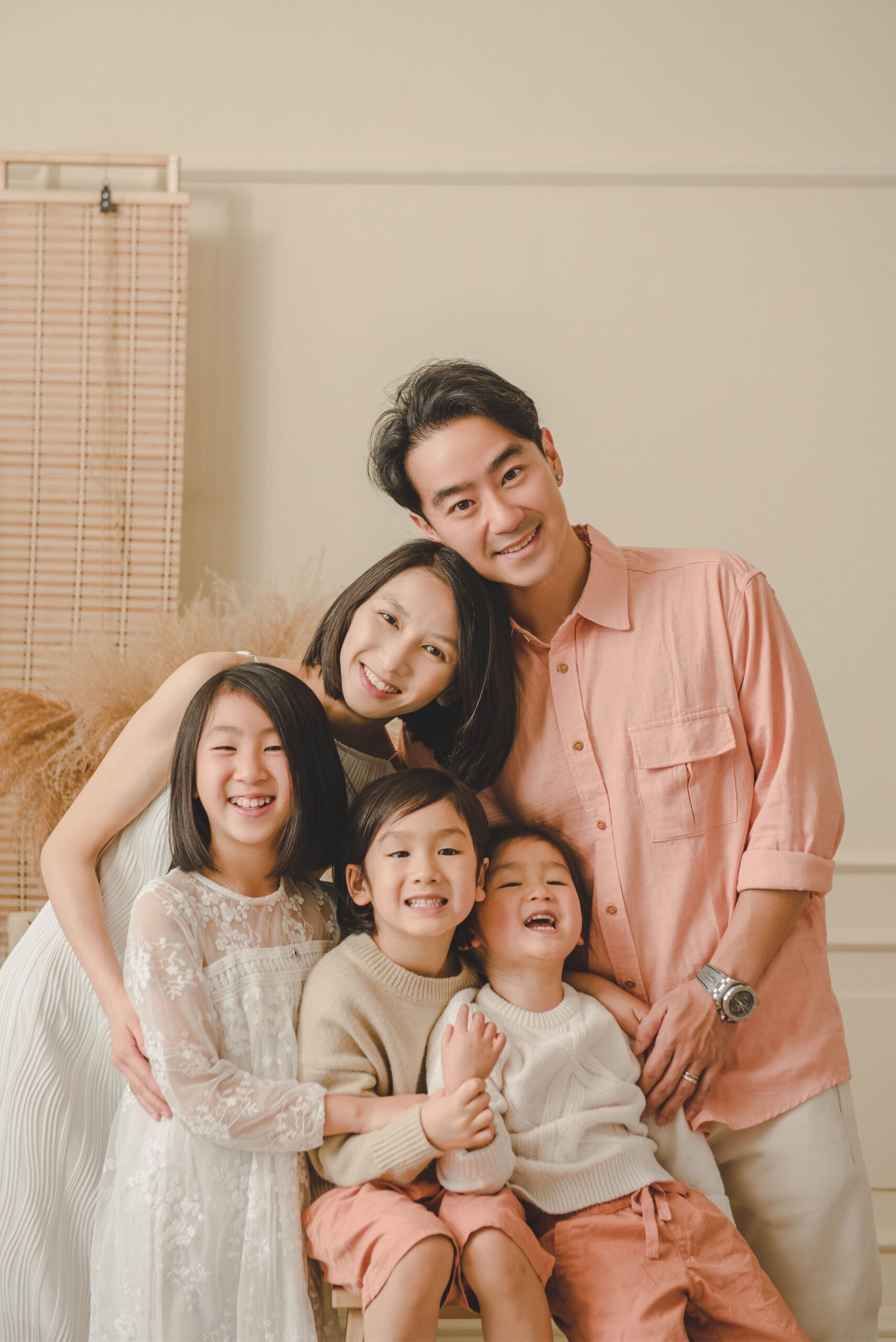Warm family portrait of parents and three children in coordinated neutral outfits