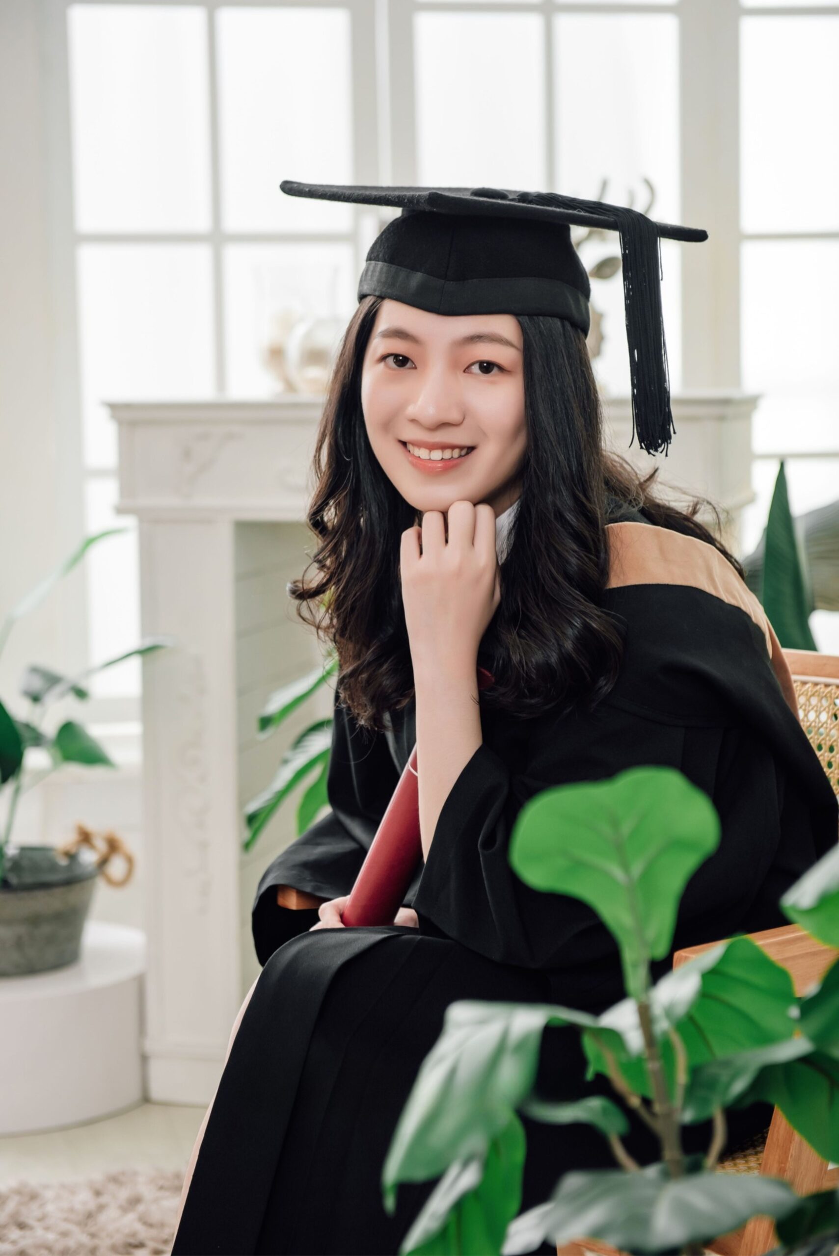 Graduation photography portrait of female graduate in cap and gown with elegant natural smile