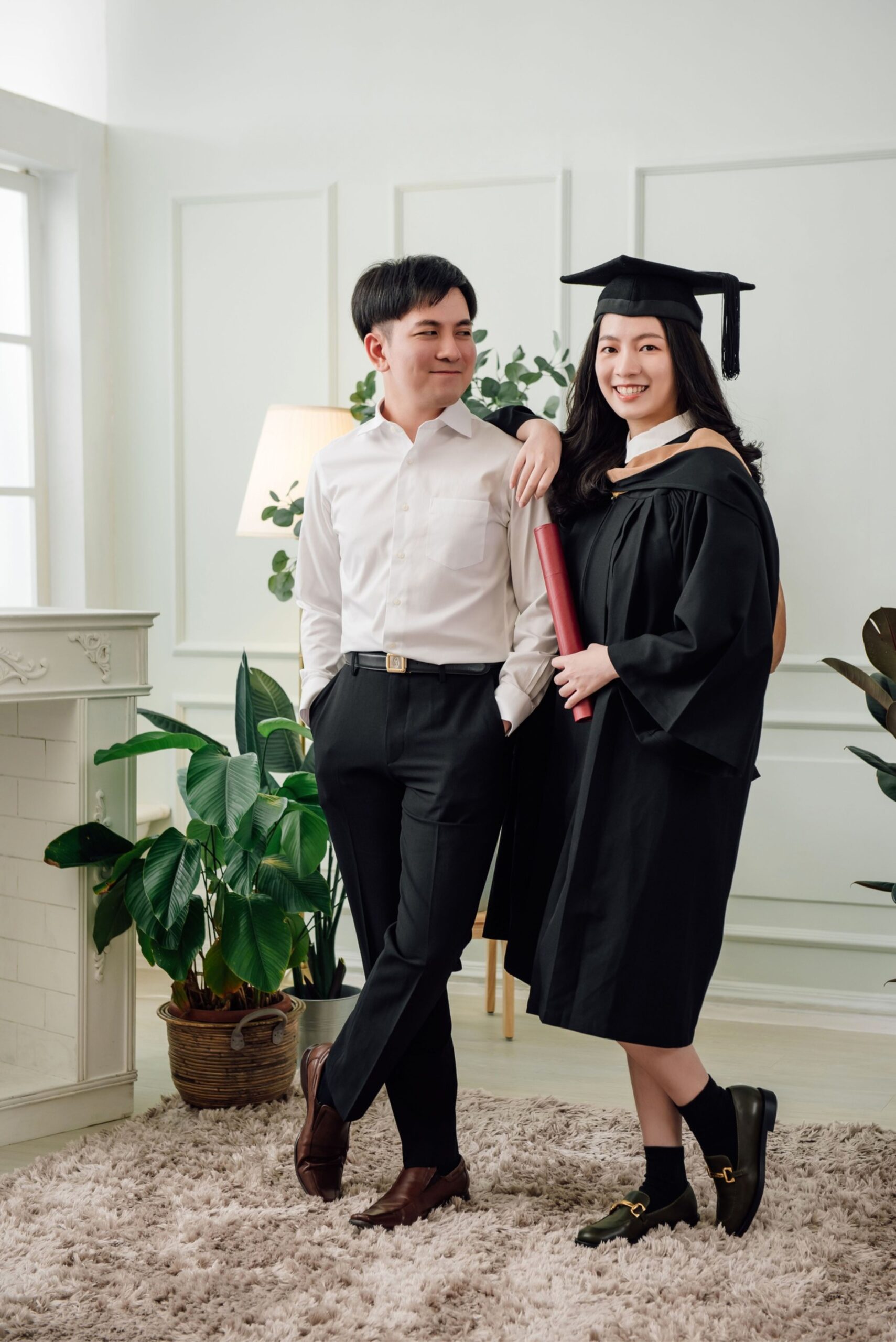 Graduation couple portrait with graduate in cap and gown celebrating with partner